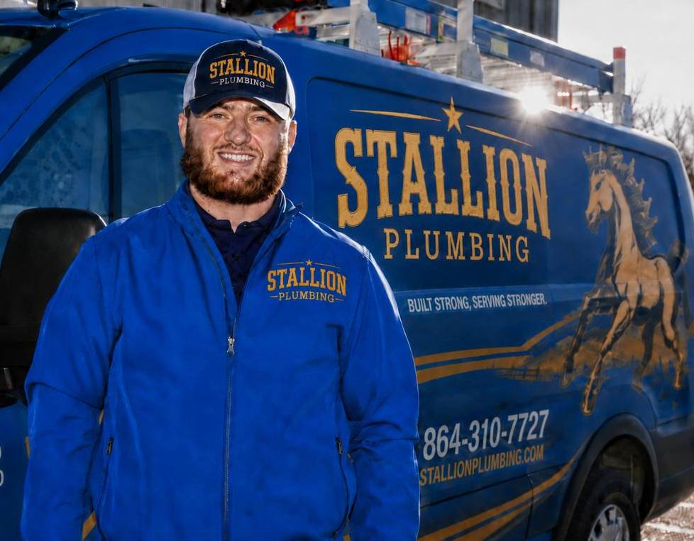 Stallion Plumbing technician in front of branded service van